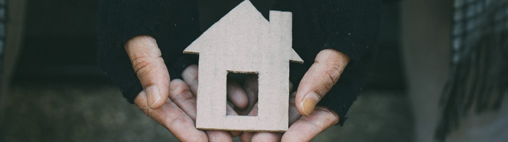 Poor tired depressed hungry homeless man holding a cardboard house.