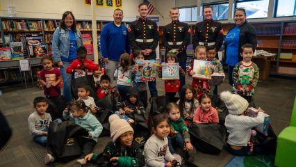 Supervisor Baca, Jr with three marines, two teachers and a group of children with new toys