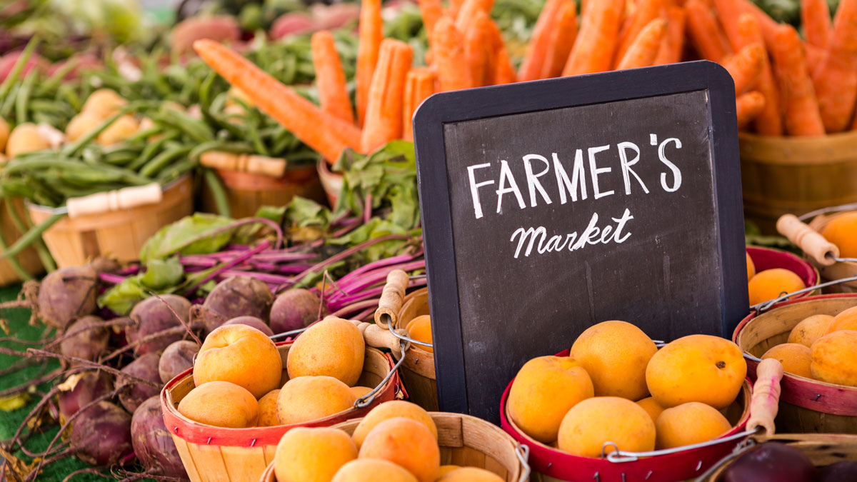 Fresh produce with a chalk board that says "Farmer's Market"