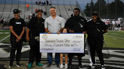 Supervisor holds check with football coaches