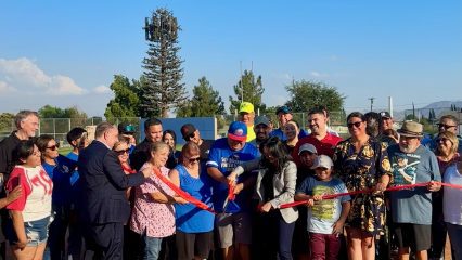 Supervisor Joe Baca, Jr., San Bernardino Mayor Helen Tran, representatives from Senator Reyes’ office, and members of the San Bernardino Pony League join community residents for a ribbon cutting ceremony celebrating the reopening of Guadalupe Field. The group gathers on the baseball diamond, smiling as they cut the red ribbon together.