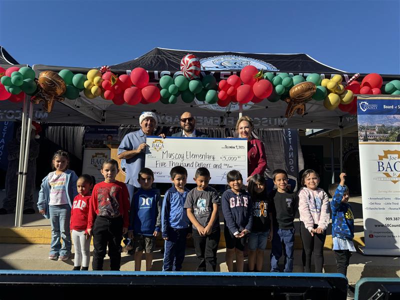 Supervisor Joe Baca, Jr. presenting Muscoy Elementary School Principal and students with $5,000 at 2025 Toy Giveaway